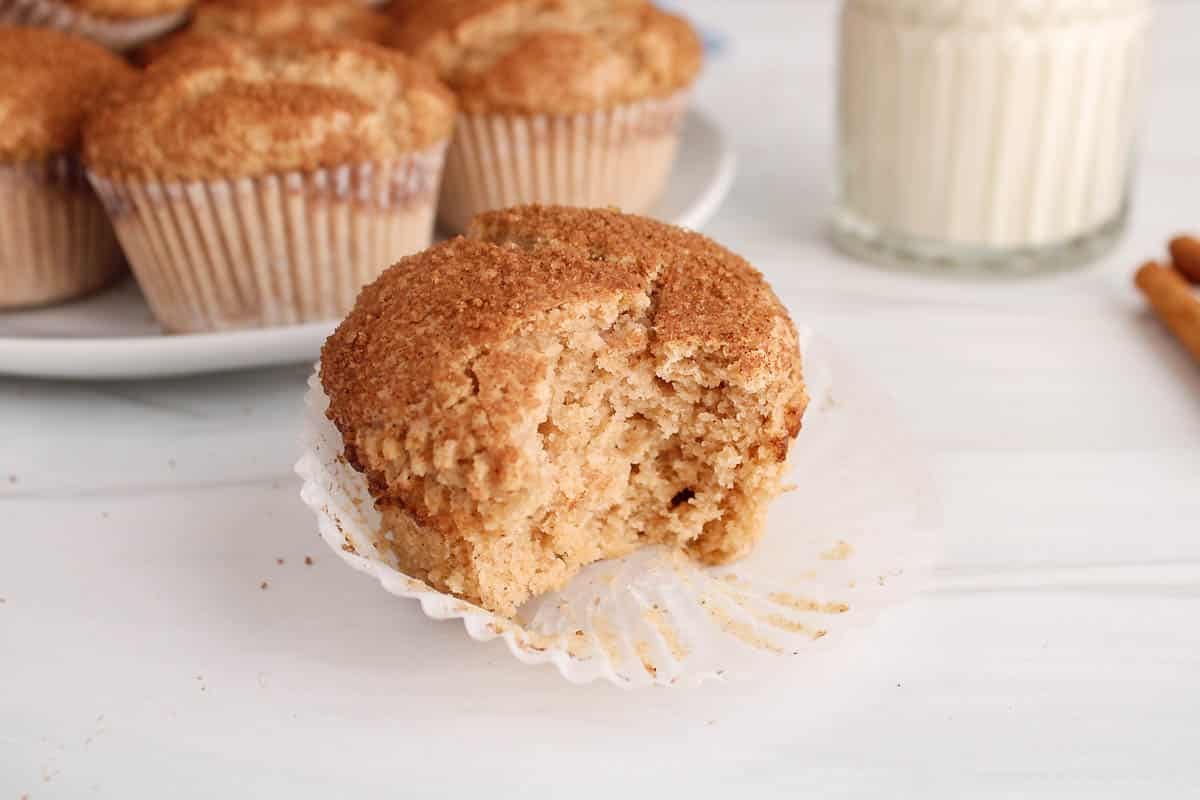 A vegan cinnamon muffins with a bite taken off to see the middle texture.