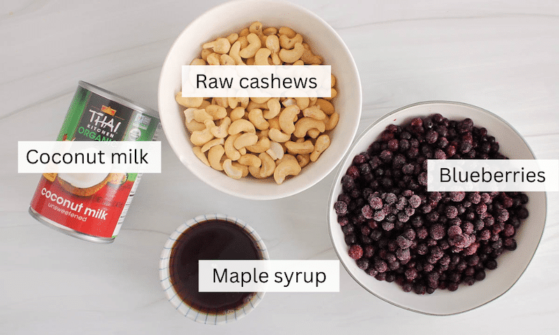 Ingredients to make a vegan blueberry ice cream on a white table.