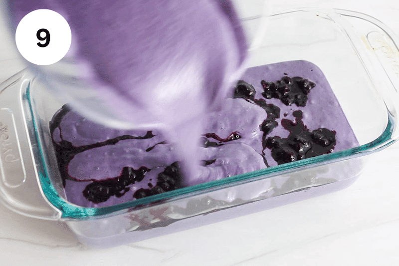 Pouring blueberry coconut mix over cooked blueberry in a glass container.