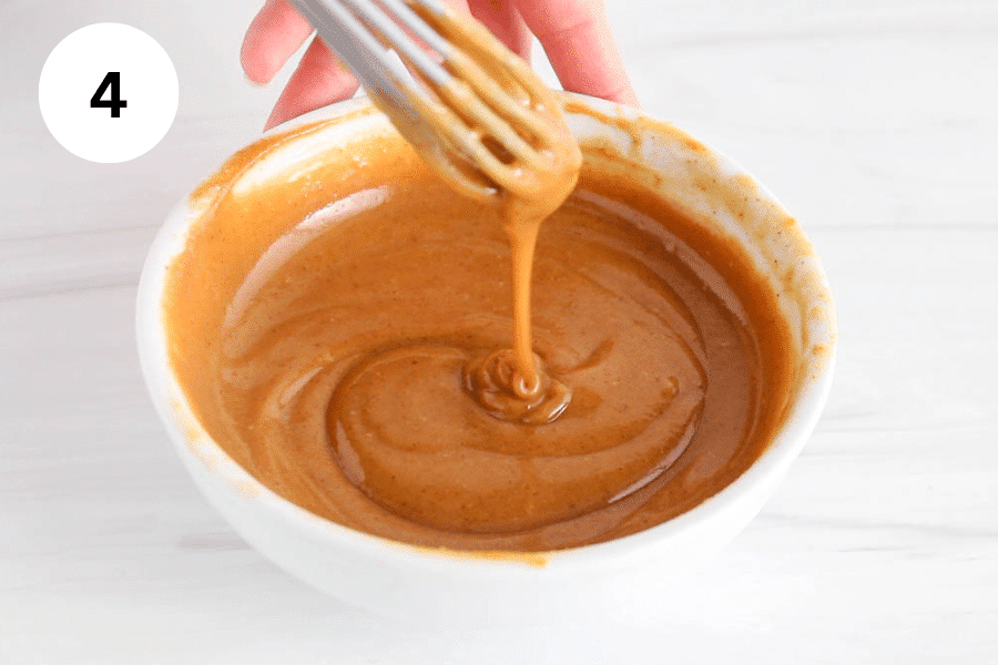 A small whisk stirring a peanut butter caramel.