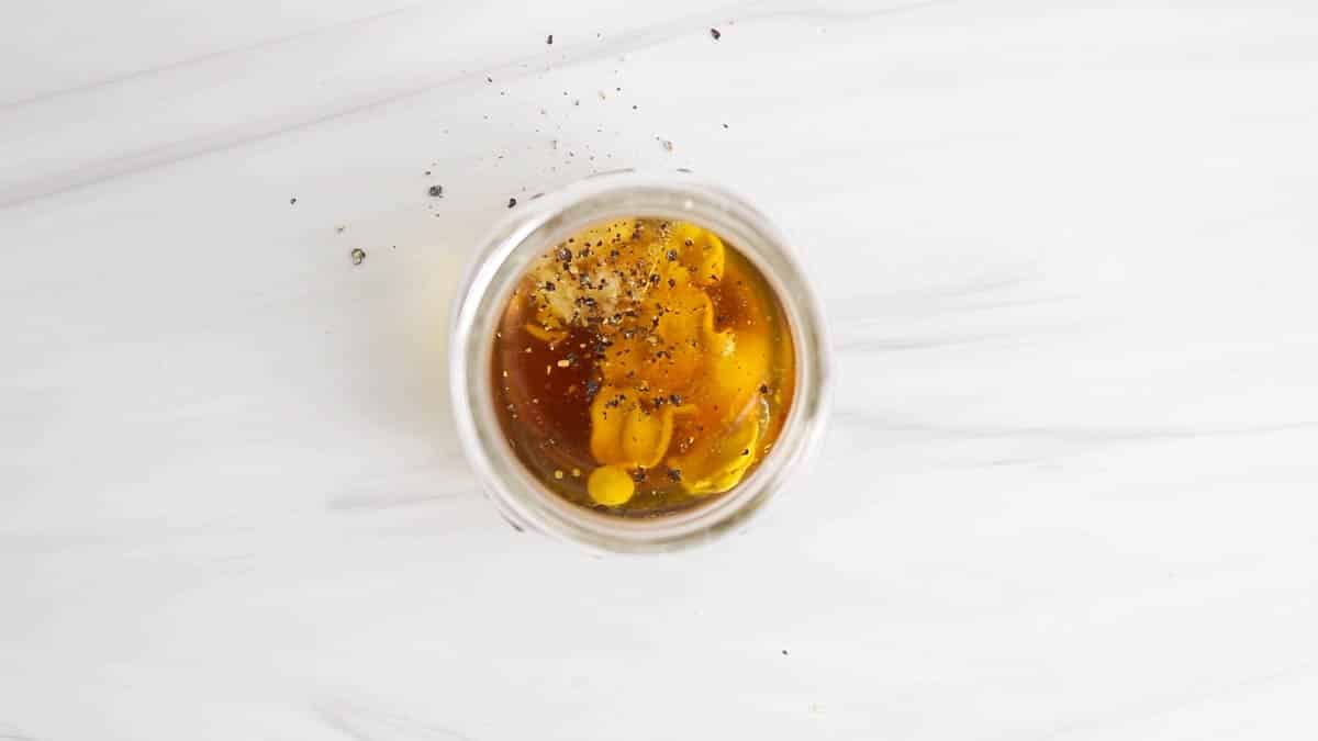 Small jar containing olive oil, apple cider vinegar, Dijon, maple syrup and salt/pepper.