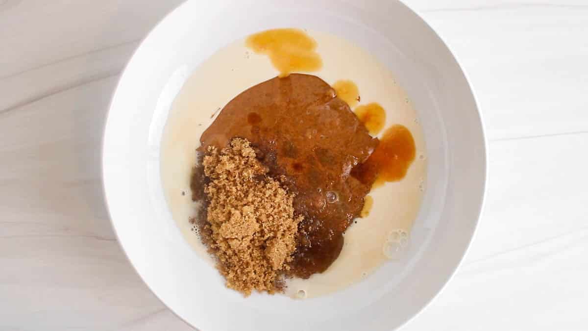Oat milk, brown sugar, almond butter and vanilla in a large white bowl.