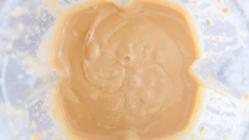 Looking into a blender filled with a peanut sauce.