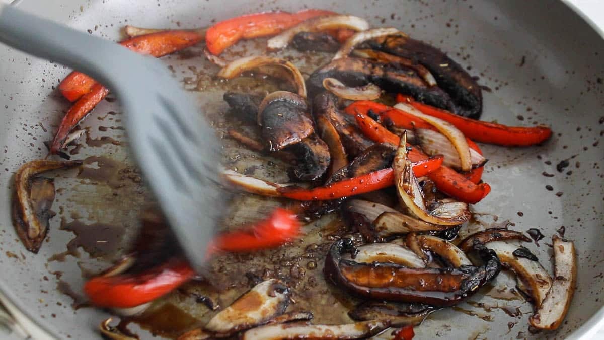 Spatula stirring cooked vegetable in a dark glaze.