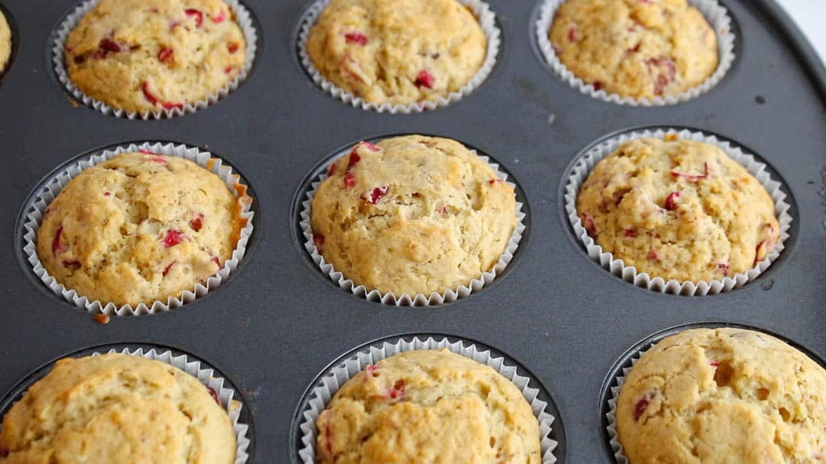 Freshly baked orange cranberry muffins in a muffin pan.