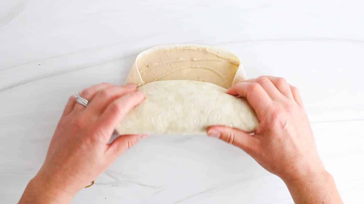 2 hands rolling a wrap into the shape of a burrito.