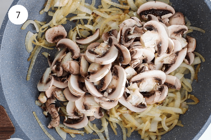 Mushrooms over caramelized onion in a pan.