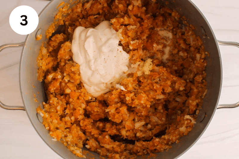 A pot with mashed sweet potato and cauliflower with yogurt and garlic over.