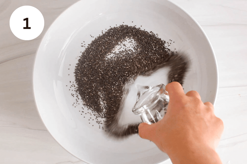 Pouring water over chia seeds in a white bowl.
