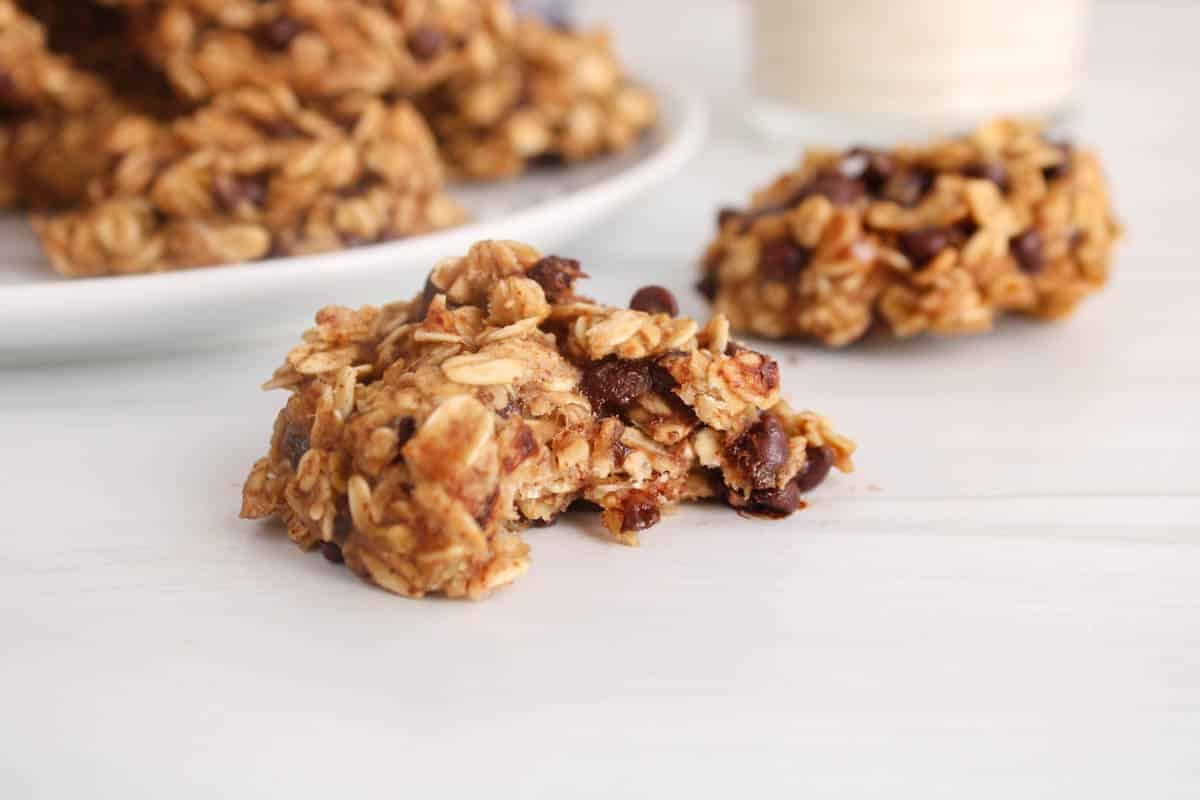 A vegan banana oatmeal cookies with a bite taken off on a white table.