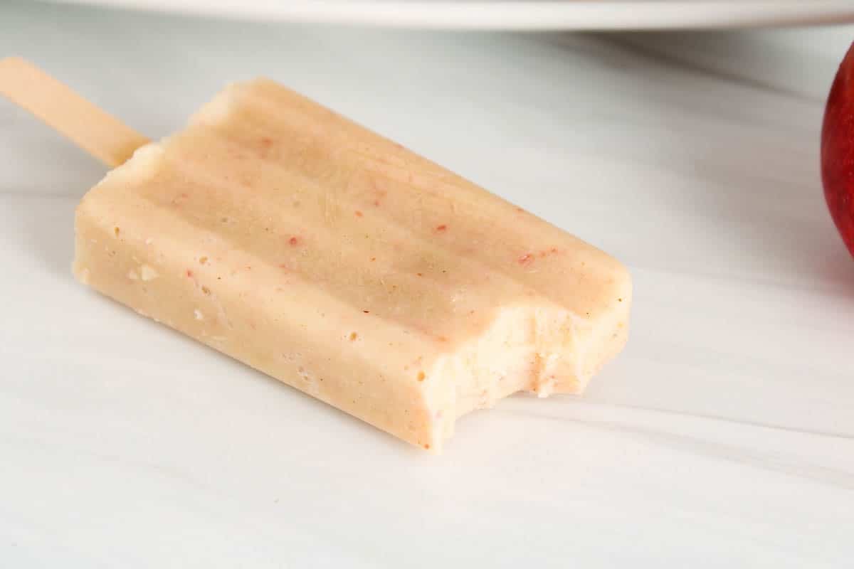 Apple popsicle with a bite taken off.