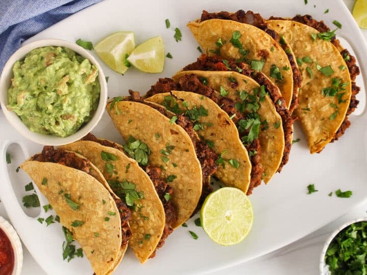 A few crispy baked tacos made with black beans and a side of guacamole.
