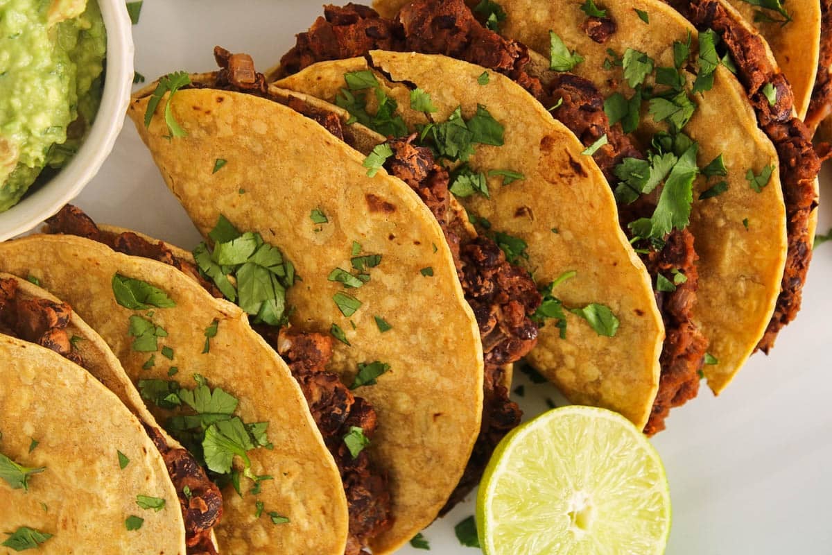 Showing some baked black bean tacos on a plate garnished with cilantro.