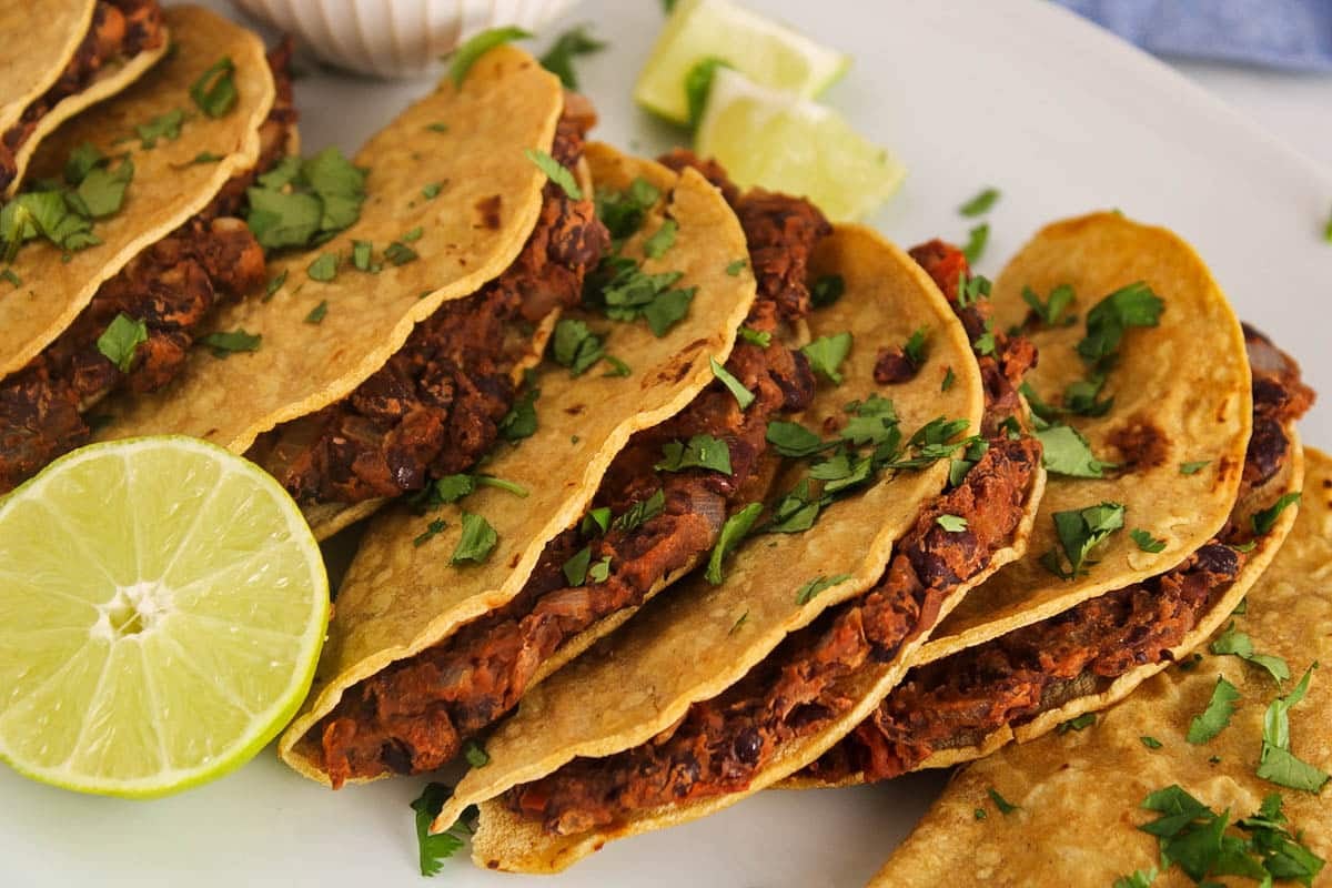 Showing the interior filling made with black beans in a few crispy baked vegan tacos.