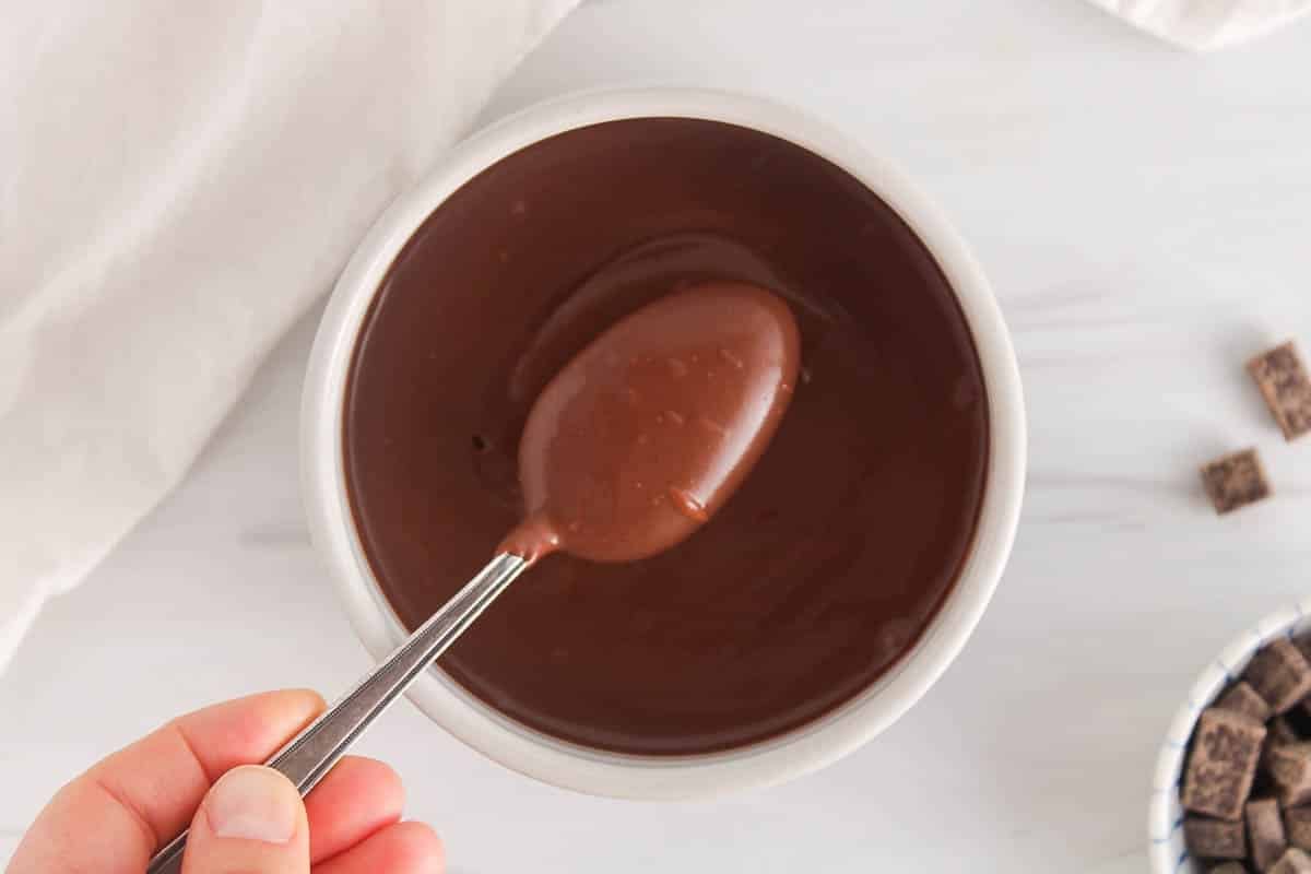 A spoon taking some vegan chocolate ganache from a bowl.