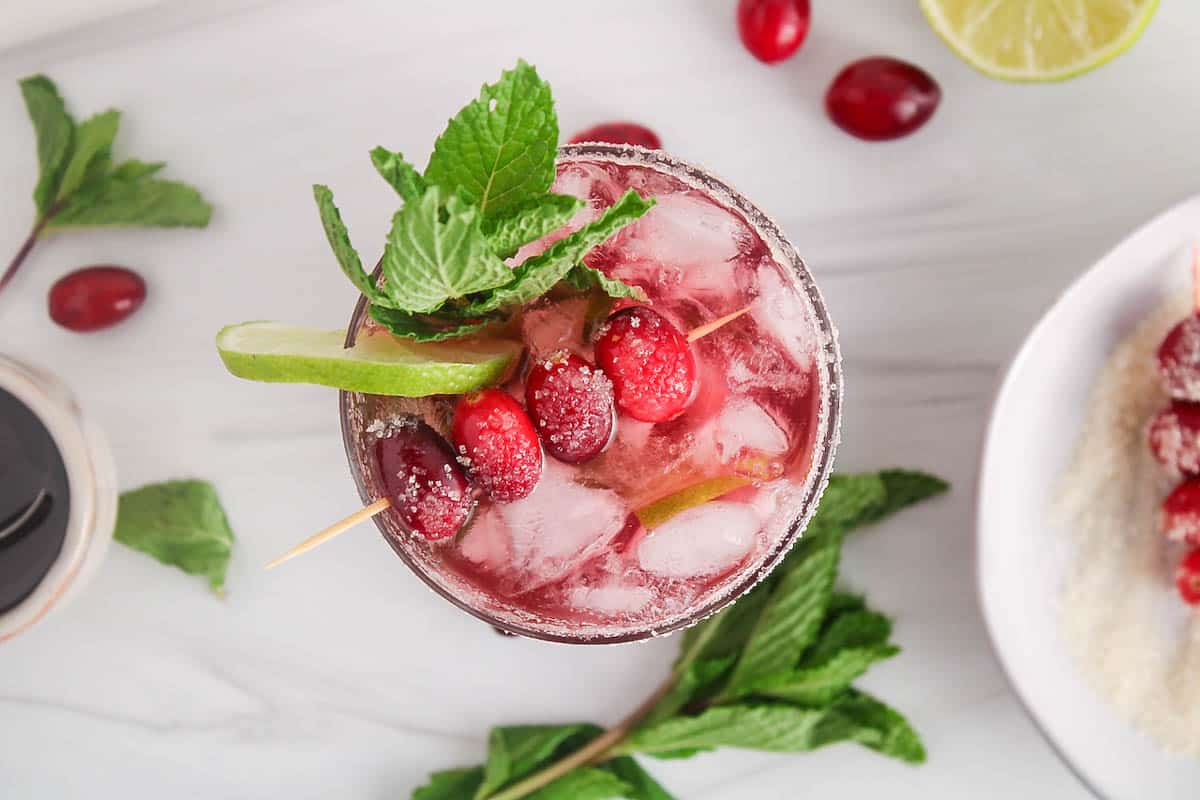 Top part of a cranberry juice mocktail decorated with fresh cranberries, slice of lime and mint.
