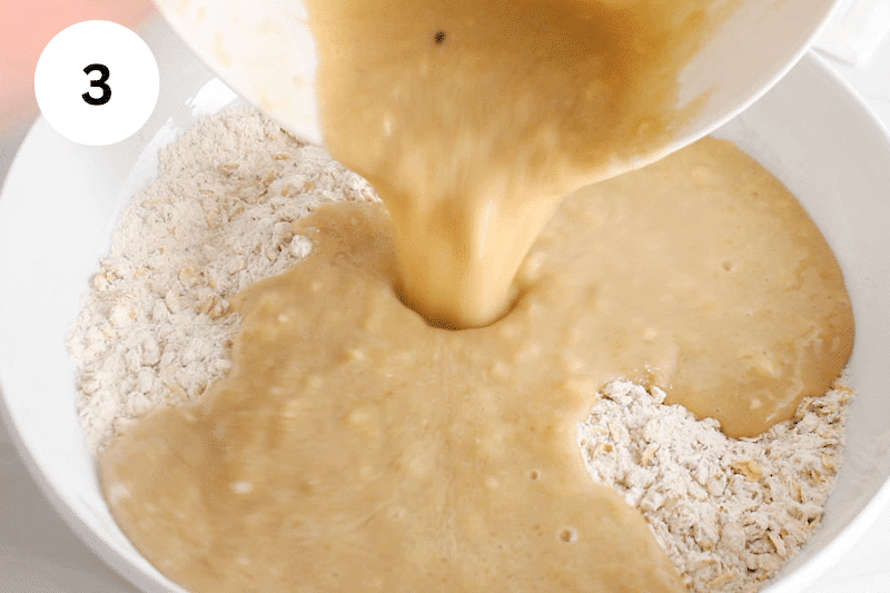 A wet mixture pouring a bowl with dry ingredients.