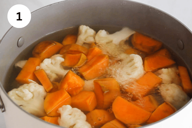 Sweet potatoes and cauliflower simmering in a pot.