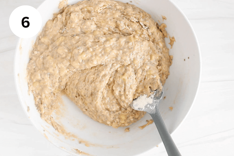 A spatula mixing a muffin batter in a large bowl.