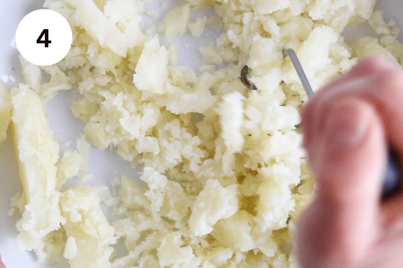A potato masher mashing potatoes.