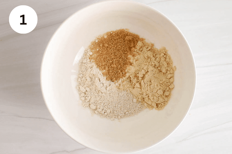 Oat flour, protein powder and sugar in a white bowl.
