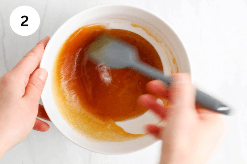 A spatula mixing a syrup mixture in a bowl.