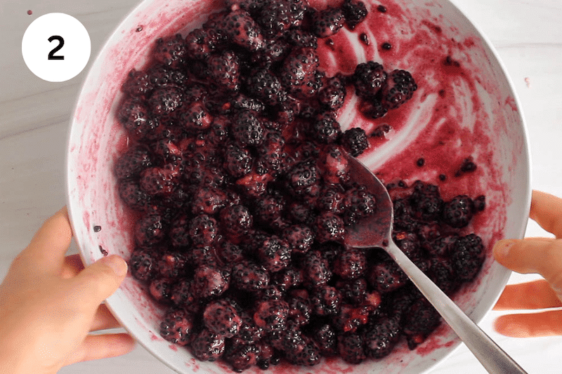 A spoon in a bowl with a blackberries cornstarch mix.