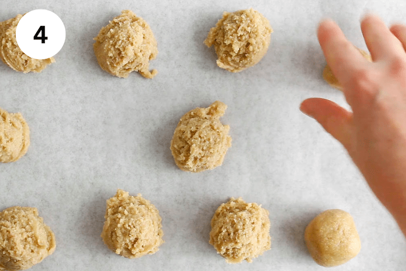 A hand shaping cookie dough in balls.