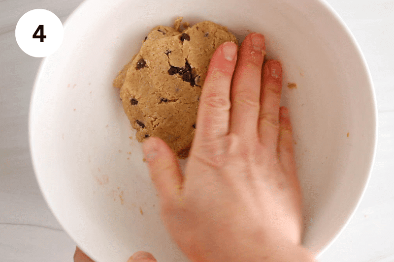 A hand in a bowl shaping a dough into a ball.
