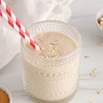 A short glass filled with a no banana peanut butter smoothie and a red and white straw.
