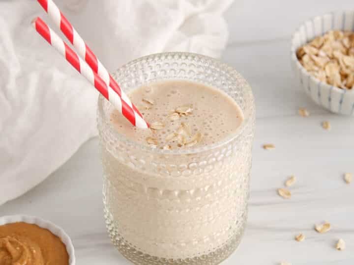 A short glass filled with a no banana peanut butter smoothie and a red and white straw.