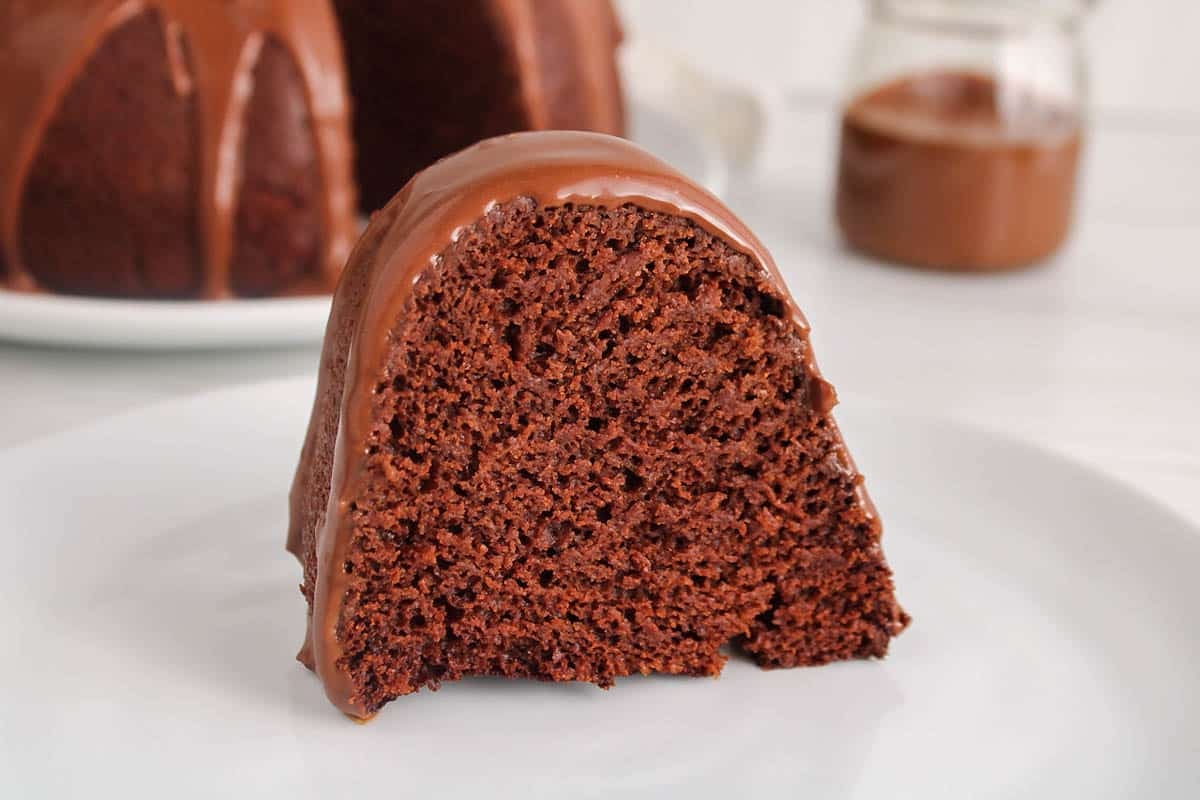 A slice of vegan chocolate bundt cake on a plate with a drizzle of vegan ganache.