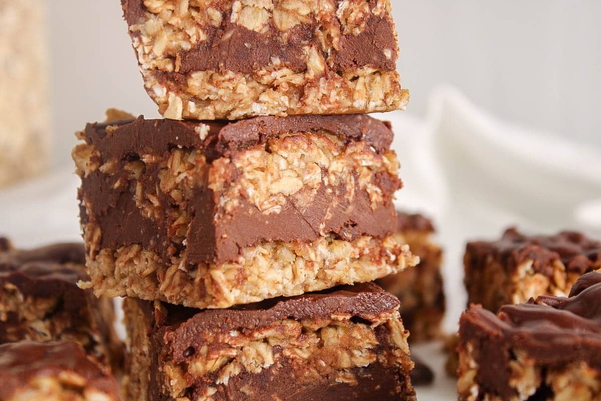 Pile of layered vegan no bake peanut butter oatmeal bars with a chocolate layer in the center.