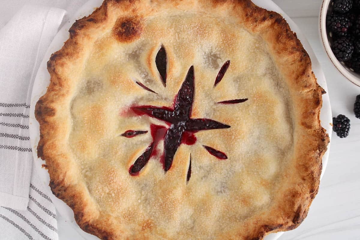 Vegan blackberry pie placed on a white counter.