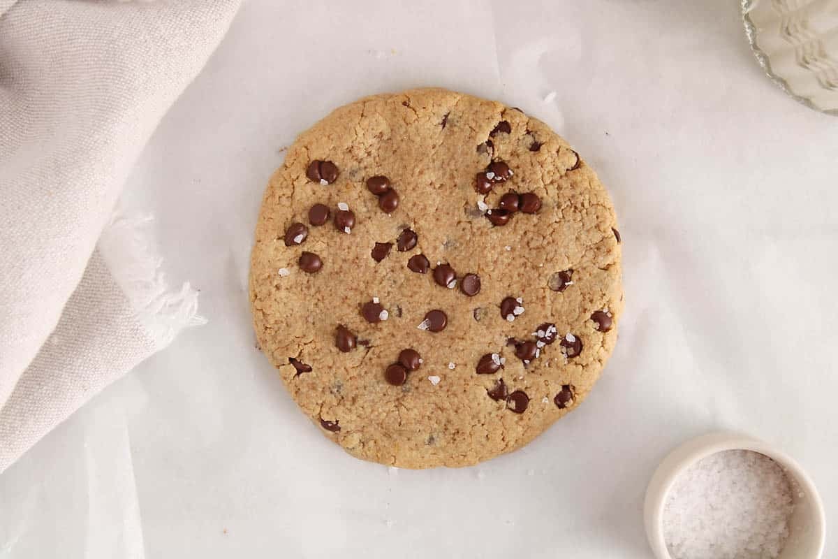 A vegan chocolate chip single serve protein cookie on a white counter.