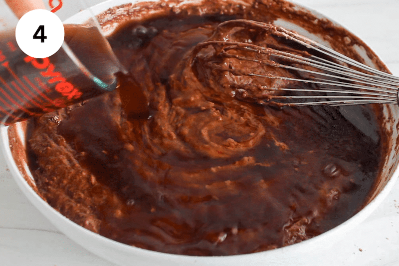 Warm coffee pouring over a chocolate cake batter in a bowl.