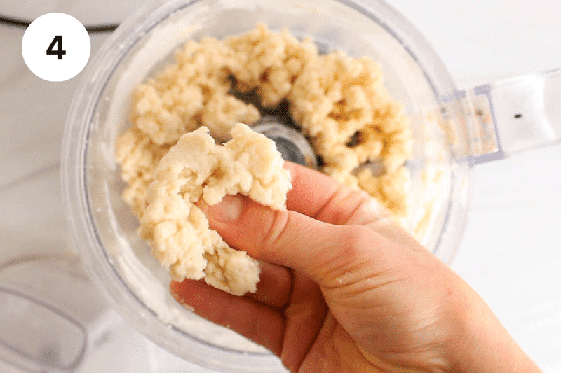 A hand squeezing some dough in between the fingers.