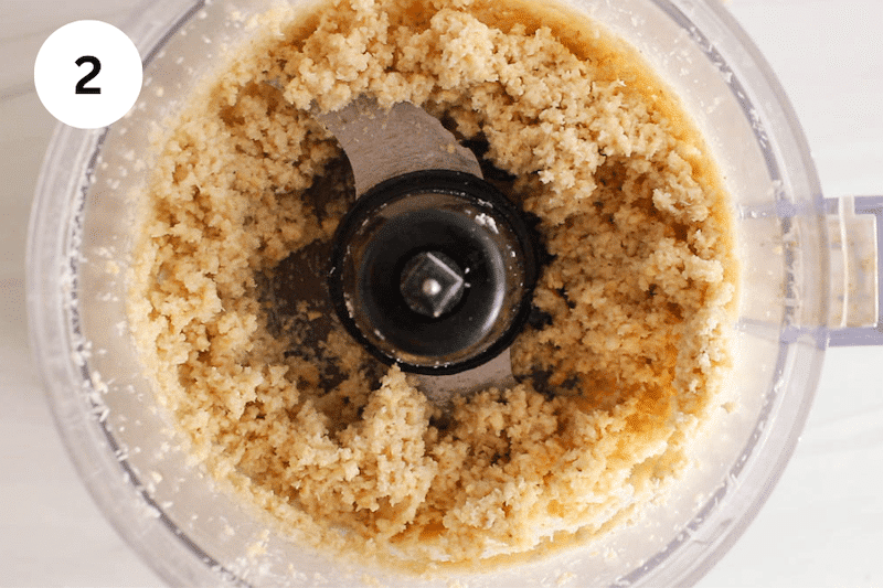 A beige sticky mixture in a food processor.