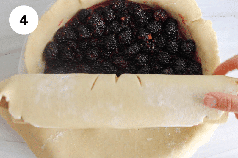 A roll pin adding a second pie crust over a blackberry pie.