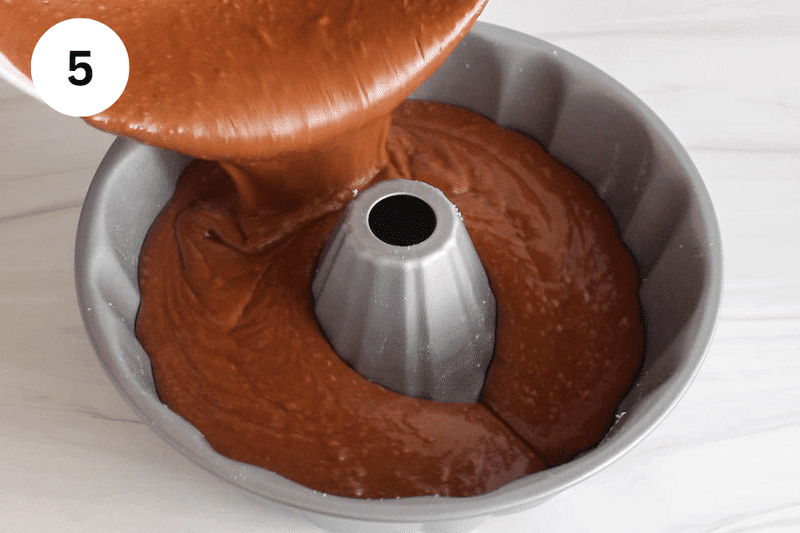 Chocolate cake pouring in a bundt cake mold.