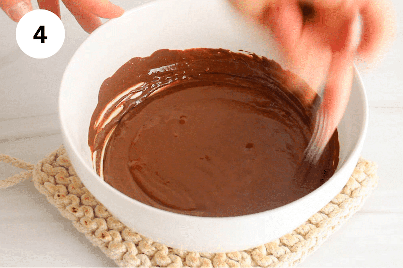 A whisk is stirring in a bowl with a chocolate sauce.