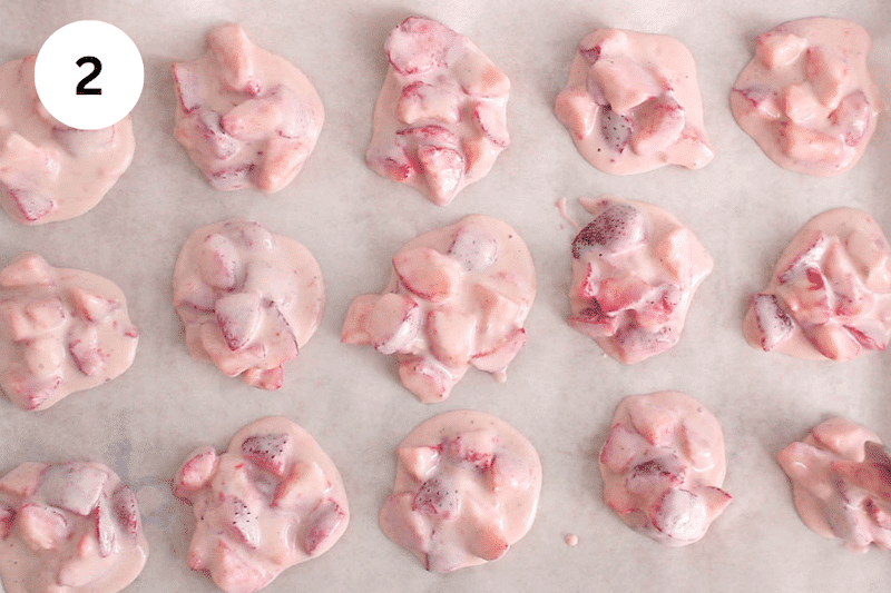 Yogurt and strawberries in clusters over a baking sheet.