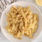 A white plate of noodles tossed in a vegan chickpea pasta sauce.