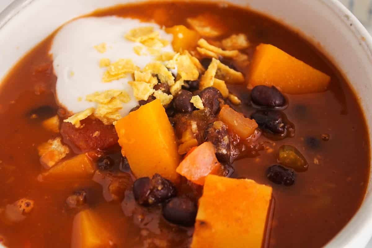 Bowl of warm black bean butternut squash soup topped with vegan sour cream.