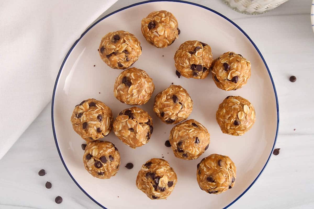 Healthy peanut butter bliss balls with chocolate chips on a white plate.