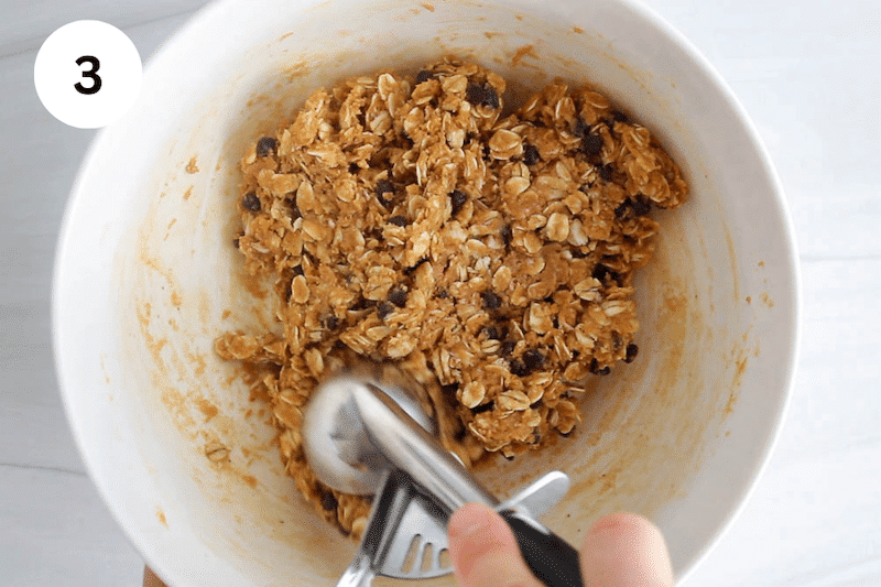 An ice cream scoop taking some oat PB mixture from a bowl.