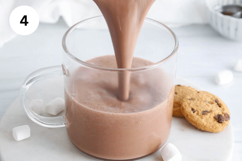 A hot chocolate mix pouring in a see-through mug.