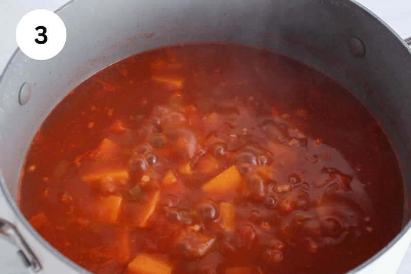 A tomato vegetable broth simmering in a large pot.