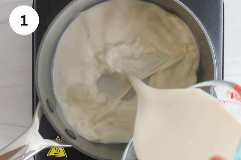 A jar pouring oat milk in a small saucepan.
