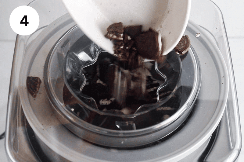 A bowl adding some chopped chocolate cookies into an ice cream maker.